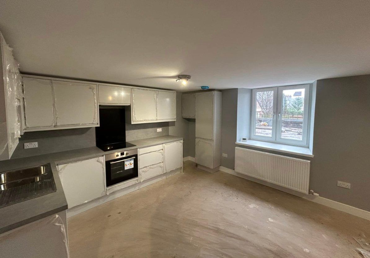 Kitchen in a basement apartment with grey walls, a radiator under the window and new units