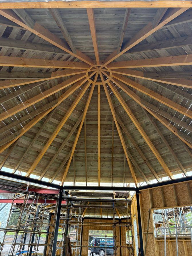 Timber rafters meeting at the centre of an octagonal roof, seen from inside