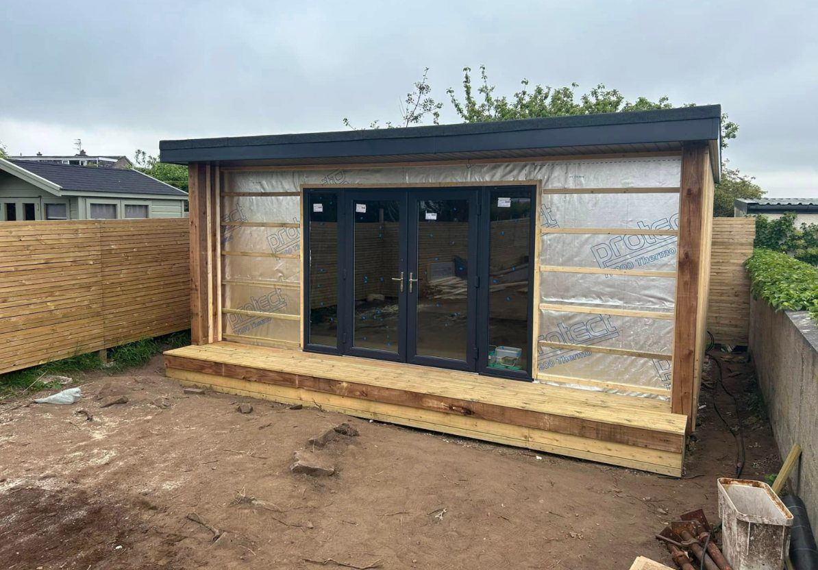 Garden room wrapped in membrane with glazed doors fitted and a deck along the front