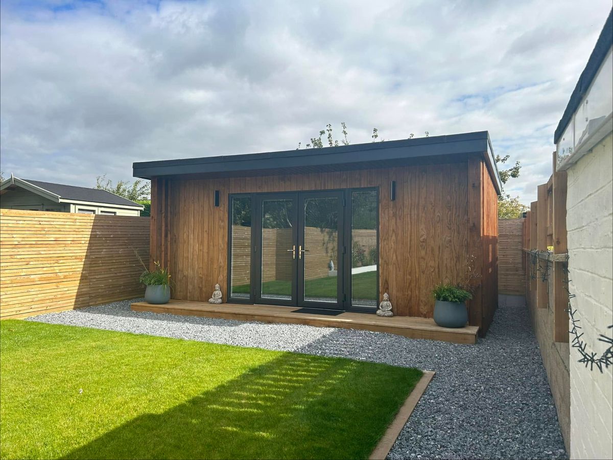 Finished timber garden room with grey doors, a deck, a gravel path and a new lawn