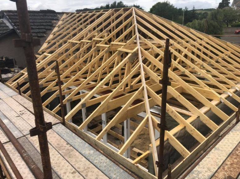 Timber roof trusses forming a hipped roof, seen from the scaffolding