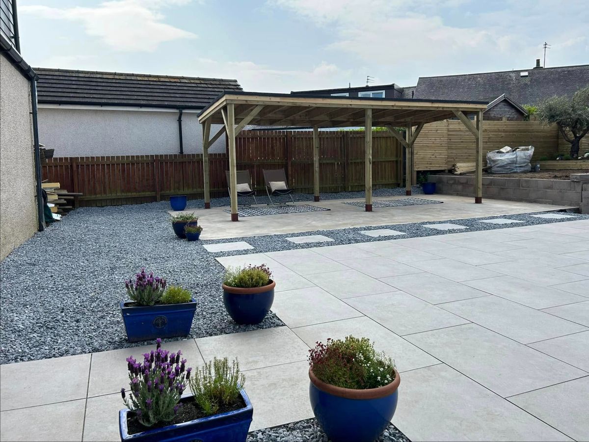 Timber pergola on a pale paved patio with gravel borders and blue planters