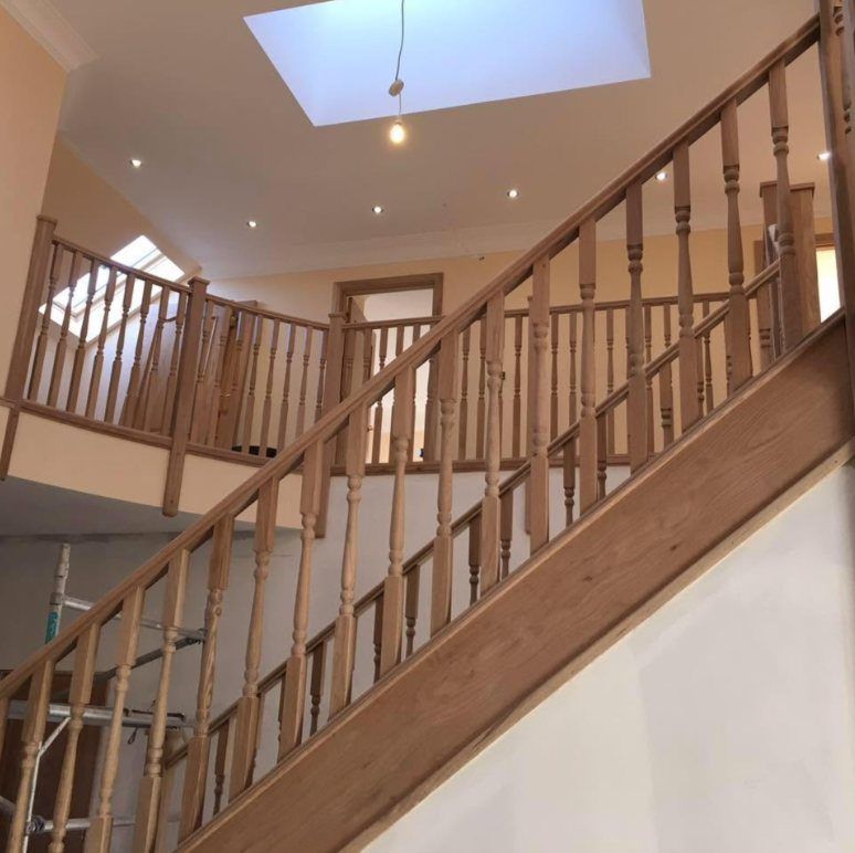 Timber staircase with turned spindles rising to a galleried landing under a roof window